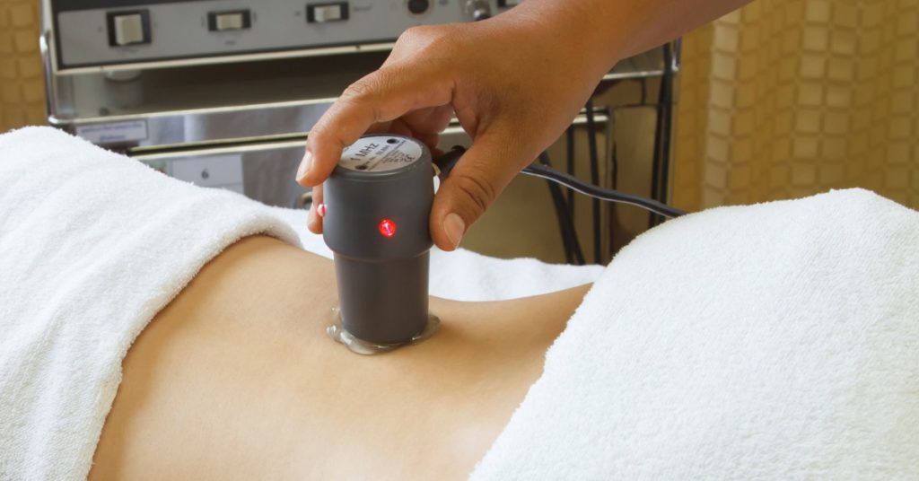 image of a hand holding a ultrasound wand to the back of a patient laying on exam table