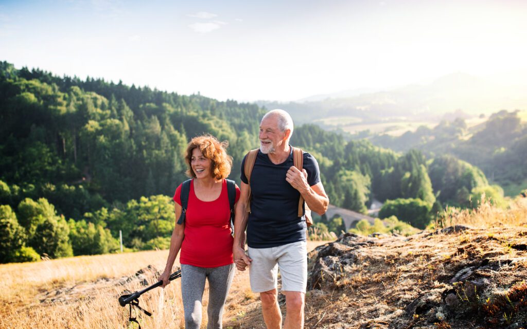 Senior tourist couple travelers hiking in nature, walking and talking.