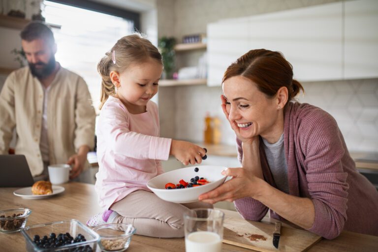 Mother and daughter bonding in the kitchen making breakfast in the morning.